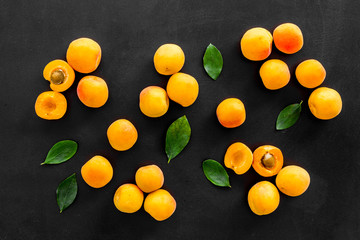 Apricots and leaves pattern on black background top view