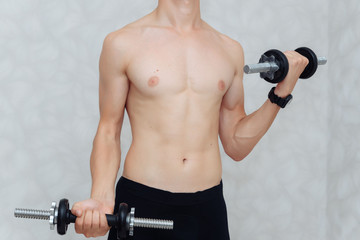 Fototapeta na wymiar Beautiful man lifting dumbbell in home. He training biceps