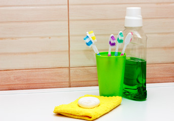 toothbrushes in green glass, dental floss and mouthwash and towel