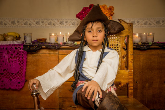 ni&ntilde;o pirata con disfraz de hallowen, y sombrero con caireles, velas y flores de sempasuchil