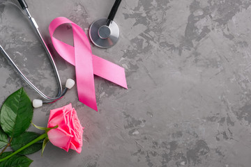 Pink ribbon, stethoscope and rose on a concrete background. Breast Cancer Awareness Month