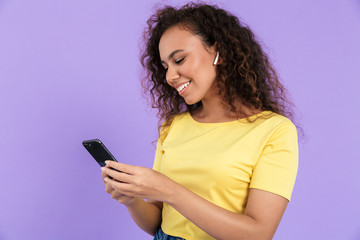 Image of positive african american woman listening to music with earpods