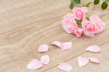 Rose petals and flowers on the wooden background.