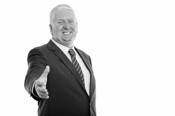 Studio shot of happy mature businessman smiling while giving handshake