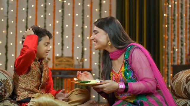Happy brother sister celebrating Raksha Bandhan / Bhai Dooj festival. On the festival of Raksha Bandhan/Bhai Dooj  beautiful elder sister putting tika on her brother's forehead - happy moment
