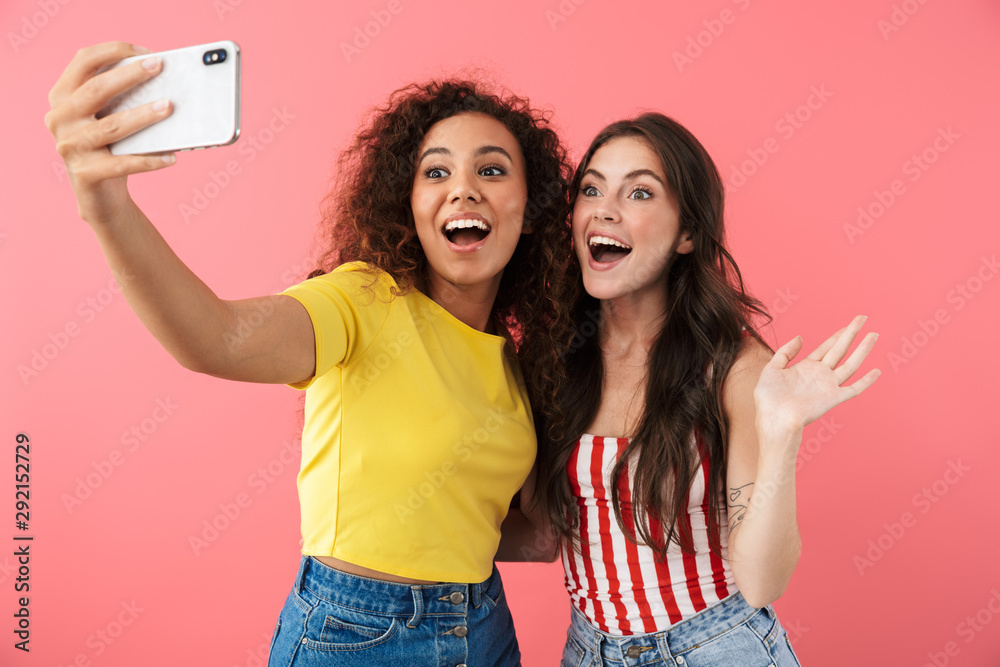 Wall mural Image of brunette multinational girls taking selfie photo on cellphone