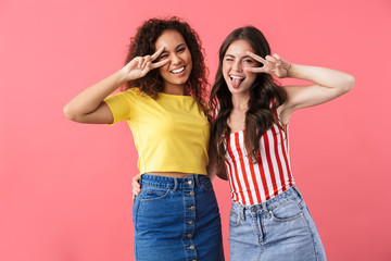 Image of young multinational girls smiling and showing peace sign together