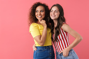 Image of pleased multinational girls smiling and looking aside at copyspace