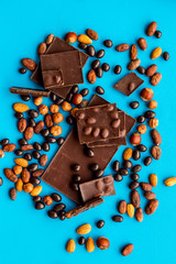 Cook homemade chocolate with bars, nuts, coffee beans on blue background top view