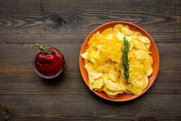 Potato crisps with tomato sauce on wooden background top view