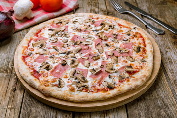 Pizza with ham and mushrooms on wooden table