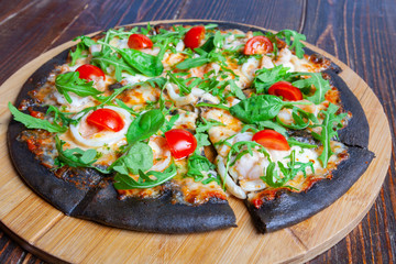 Pizza on black dough with arugula and cherry