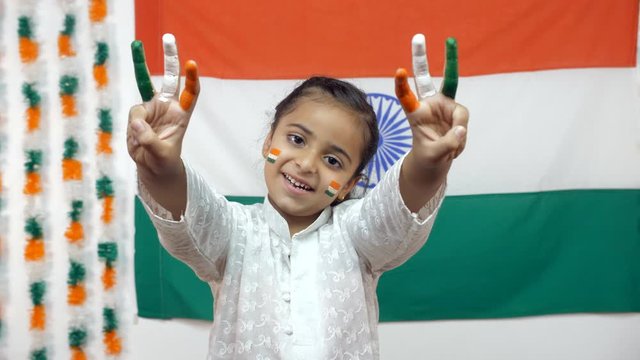 Little Indian girl with her fingers painted with national tri colors - Independence day arts concept. Cute school going girl shows her creativity by painting her fingers with Indian flag colors - R...