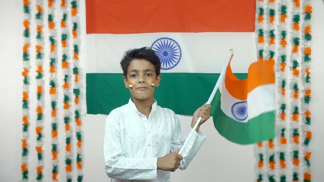 Little Indian boy enthusiastically celebrating Independence Day / Republic Day - National Tri-color flag. The little charming boy proudly celebrating 15 August / 26 January with joy - Festive Celeb...