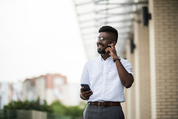 Indian man with earphones, smartphone listening to music on the street