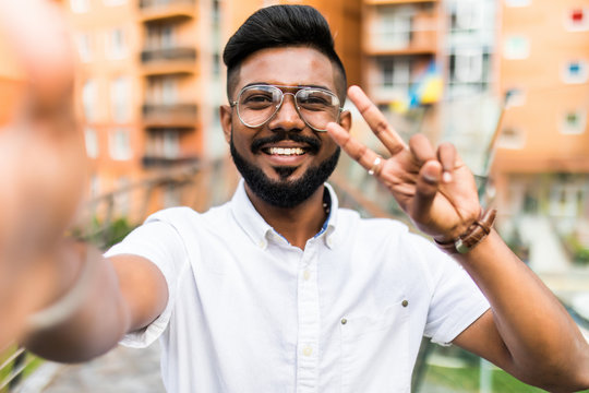 Excited indian man taking a selfie with mobile phone on the street