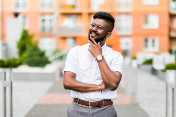 Happy bearded Indian modern young businessman smiling in the streets outdoors