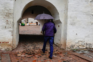 Fototapeta na wymiar Turku, Finland A man with umbrella enters the main vaulted gate at the 13th century medieval Turku Castle