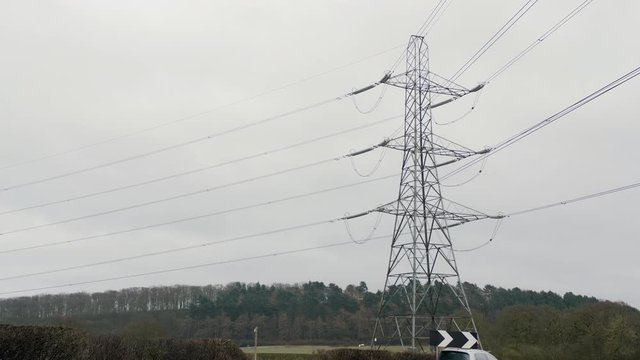 4K electric power pilons, country power supply UK England Traffic Passing Under