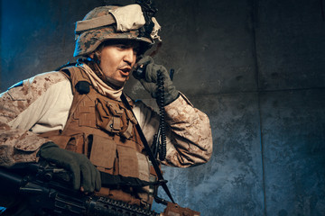 Fototapeta premium Young man in military outfit a mercenary soldier in modern times on a dark background in studio