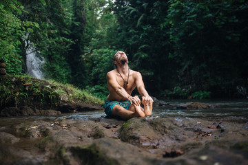 Yoga practice and meditation in nature. Man practicing near river