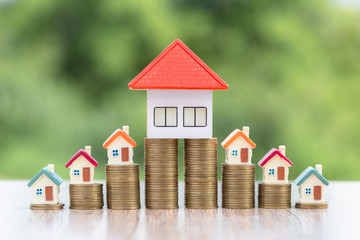 Model house on a coin, placed near the orange roof house, coins, investment concepts, finance, accounting, stock market, real estate, mortgage, take time to make money to buy a house.