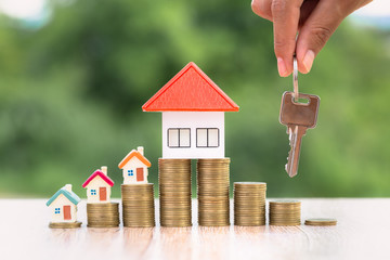 Real estate agents hold house keys for clients. House on the coin ladder Ideas for real estate, mobile homes or rental of real estate, business people holding the keys for buying and selling houses.