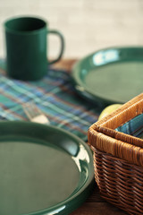 Wooden basket for picnic with plates, cups and silverware close up