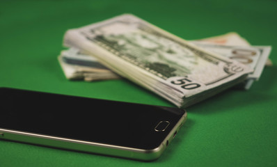 many packs of cash and phone lying on a green background