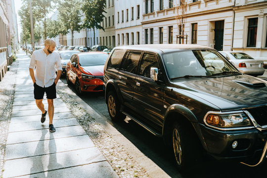 man is checking out cars on the street