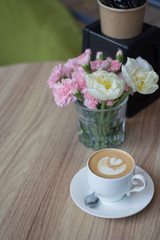 A cup of hot latte art coffee on wooden table background