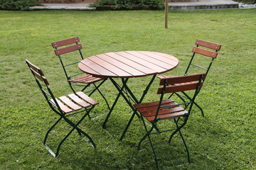 vier leere Holzstühle und ein runder Holztisch im Garten