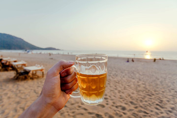 Sunset with beer in a hand. Vacation on a calm sunny beach