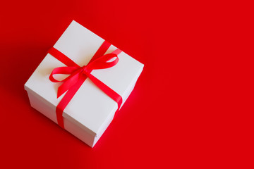 Big white box with a red ribbon on a red background top view, copy space. Big sale concept