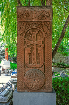 Medieval khachkar covered with carved ornaments and figures of pigeons with a circle of intertwined plants in the park of "Zoravor" church in Yerevan