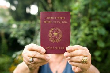 Adult woman holding her Italian passport in hands, red, identity document used to cross borders and...