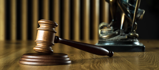 Law and Justice concept. Mallet of the judge, books, scales of justice. Gray stone background, reflections on the floor, place for typography. Courtroom theme.