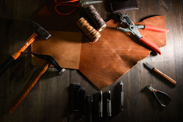 Leather craft or leather working. Leather working tools and cut out pieces of brown leather on craftman's work desk .