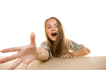Fototapeta premium Young astonished woman opening the biggest postal package isolated on white. Shocked female model on top of cardboard box looking inside. Gift, present, delivery, shipment, sales, black friday concept