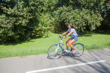 Fototapeta premium Young Woman Riding Bicycle In The Park