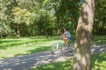 Naklejka premium Young Woman Riding Bicycle In The Park