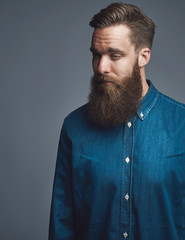 Bearded young man standing pensively against a gray background