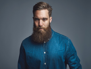 Bearded young man praying against a gray background