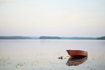 Landscape with a boat on the lake at sunset. The image has a lot of space suitable for placing text.