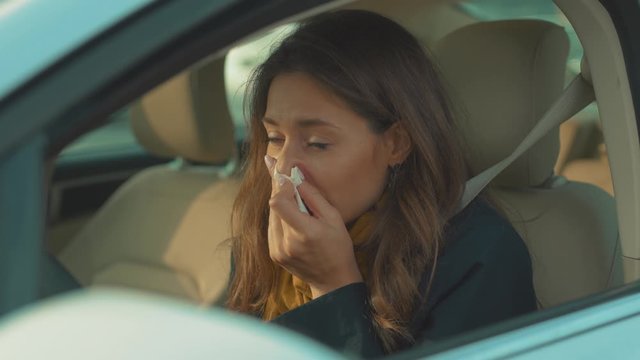 Sick young woman sitting in car sneeze holds a handkerchief vehicle influenza health illness flu medical sickness problem business infection headache slow motion
