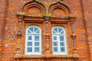 Two rounded windows on old red brick wall