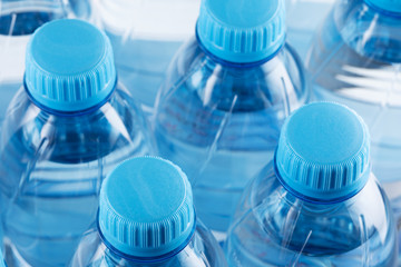 Necks of plastic bottles with still mineral water with blue caps. Rows of plastic bottles, close up