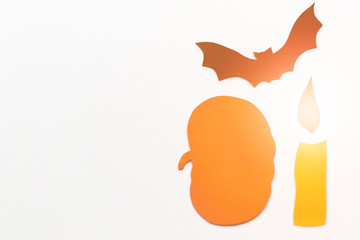 Halloween decorations with paper pumpkins, bats, candles on white background. Halloween and decoration concept. Lens flare effect. Flat lay, top view, copy space