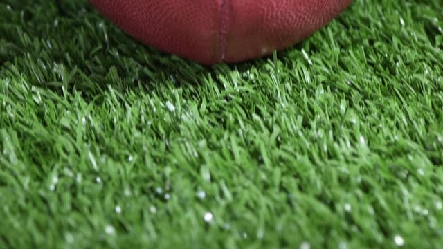 A tilt shot close-up of an American Football on the turf. 