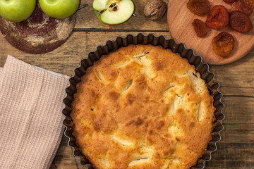Apple Pie Charlotte on a wooden table with green apples in iron form.